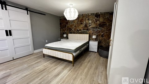 A bedroom with a bed, nightstand, and a wall with a stone pattern.