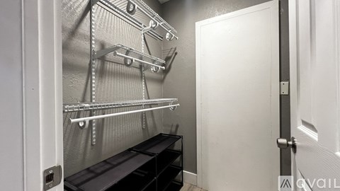 A white door is open to a walk-in closet with shelves and a bench.