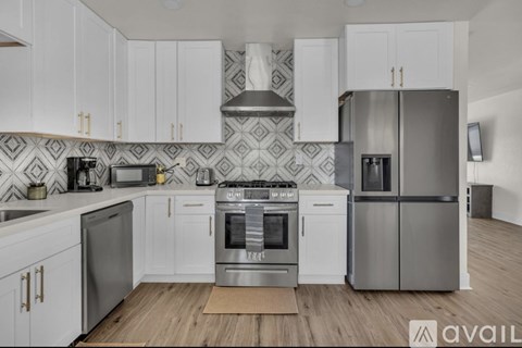 A kitchen with white cabinets and a patterned backsplash.