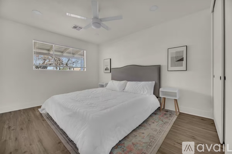 A bedroom with a large bed and a window overlooking trees.