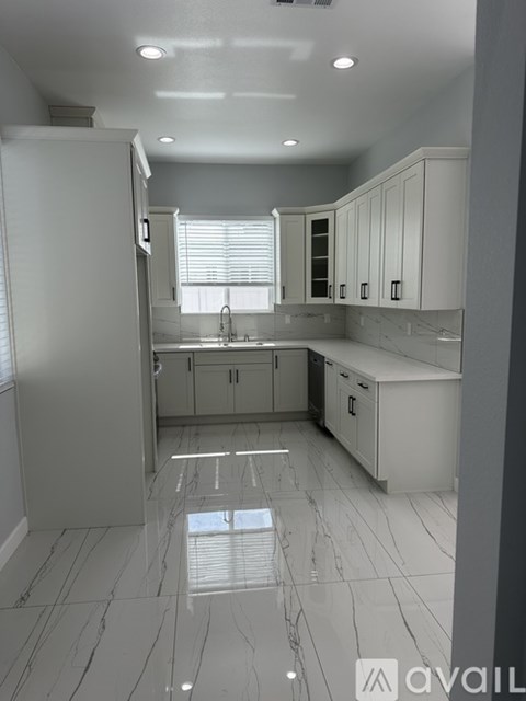 A kitchen with white cabinets and a marble floor.