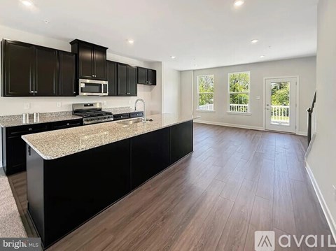 A kitchen with black cabinets and a wooden floor.
