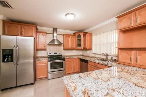 A kitchen with orange cabinets and a marble countertop.