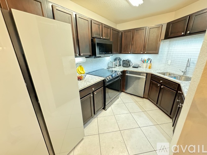A kitchen with a white refrigerator and brown cabinets.