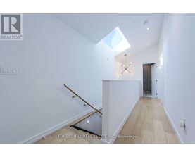 A white interior space with a skylight and a wooden staircase.