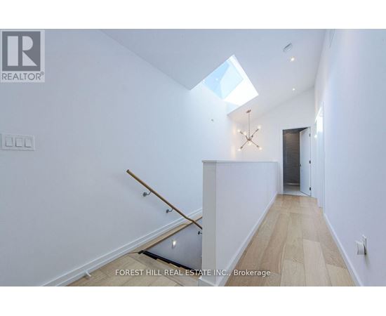 A white interior space with a skylight and a wooden staircase.