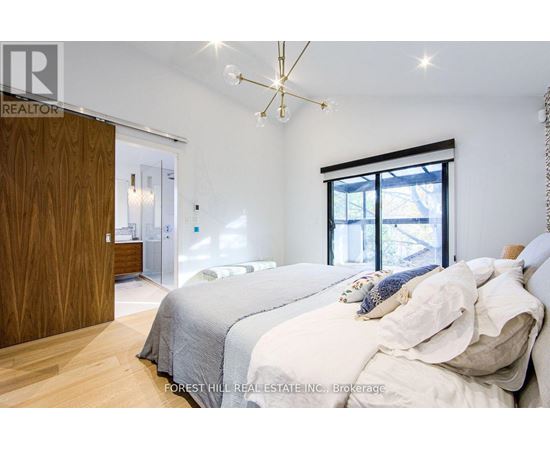 A bedroom with a large bed and a chandelier.