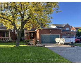 A tree with yellow leaves stands in front of a brick house.