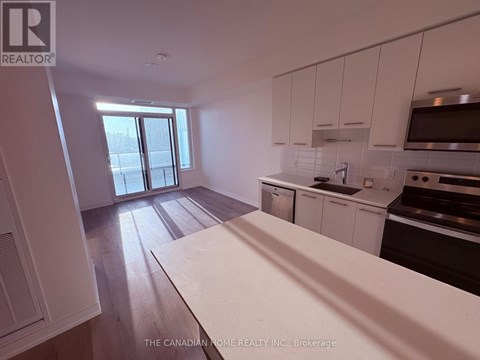 A kitchen with white cabinets and a wooden floor.