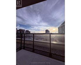 A view from a balcony overlooking a parking lot and buildings.