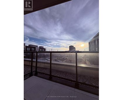 A view from a balcony overlooking a parking lot and buildings.