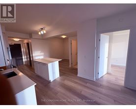 A realtor photo of a white kitchen with wood floors and a white island.