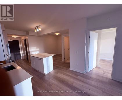 A realtor photo of a white kitchen with wood floors and a white island.
