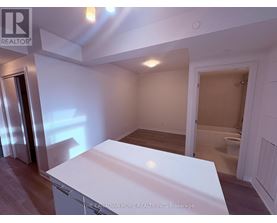 A white kitchen island in a room with a toilet in the background.