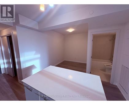 A white kitchen island in a room with a toilet in the background.
