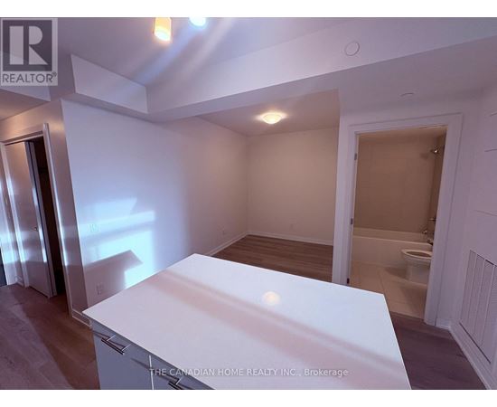 A white kitchen island in a room with a toilet in the background.