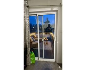 A room with a glass door leading to a balcony with lights on it.