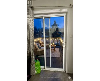 A room with a glass door leading to a balcony with lights on it.
