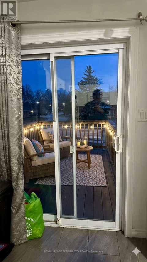 A room with a glass door leading to a balcony with lights on it.