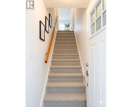 A staircase with a beige carpet and a white door.
