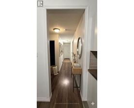 A hallway with a wooden floor and white walls.