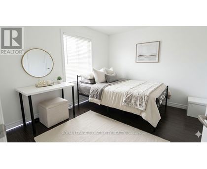 A bedroom with a bed, a table, and a round mirror on the wall.