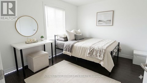 A bedroom with a bed, a table, and a round mirror on the wall.