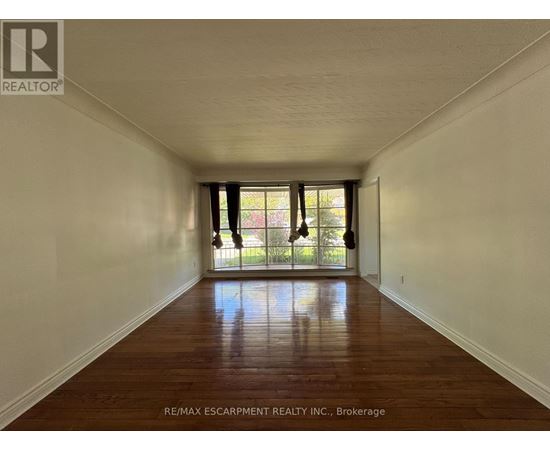 A long hallway with wood floors and white walls.