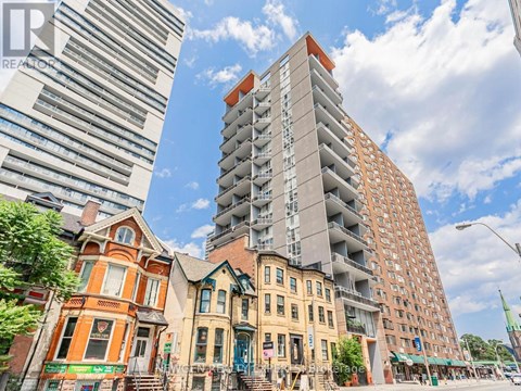 A tall building with a red top stands next to a row of older buildings.