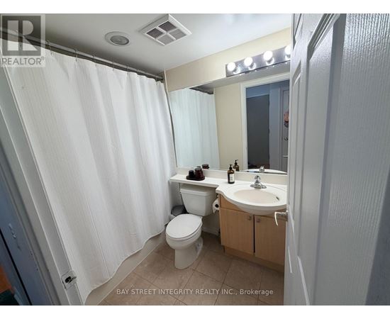 A white bathroom with a toilet, sink, and shower curtain.