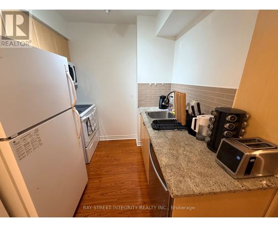 A kitchen with a refrigerator, toaster, and coffee maker.