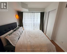 A bedroom with a large bed and a window with curtains.