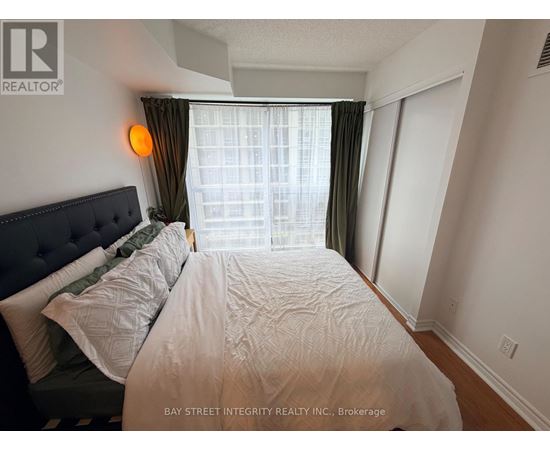 A bedroom with a large bed and a window with curtains.