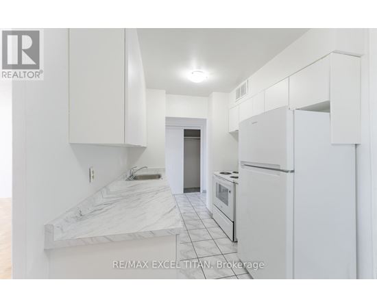 A white kitchen with a marble counter top and white cabinets.