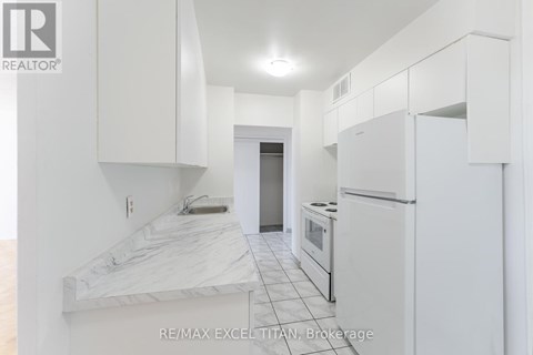 A white kitchen with a marble counter top and white cabinets.