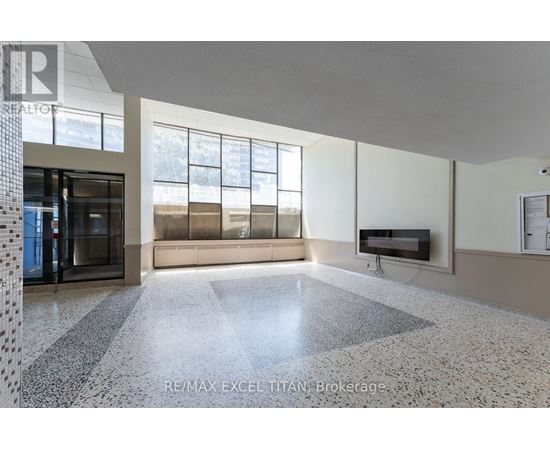 A spacious room with a tiled floor and a television mounted on the wall.
