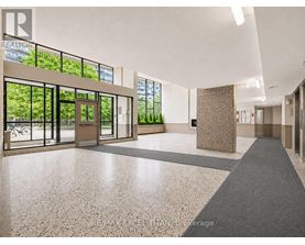 A hallway with a tiled floor and a large window with a view of trees.