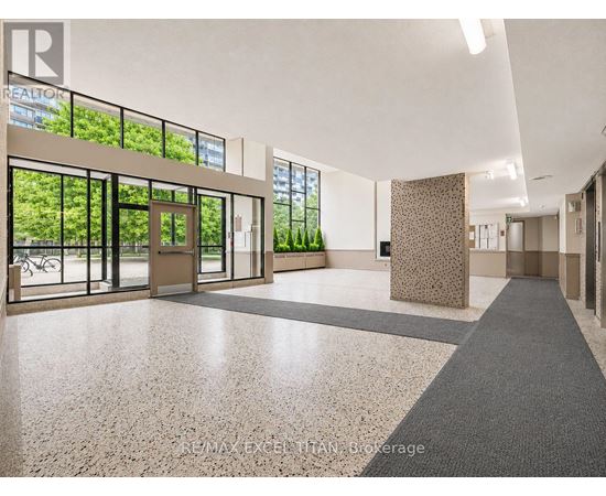 A hallway with a tiled floor and a large window with a view of trees.
