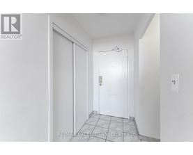 A white door with a glass window is in the middle of a white hallway.