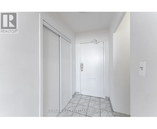 A white door with a glass window is in the middle of a white hallway.