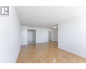 A large, empty room with wooden flooring and white walls.