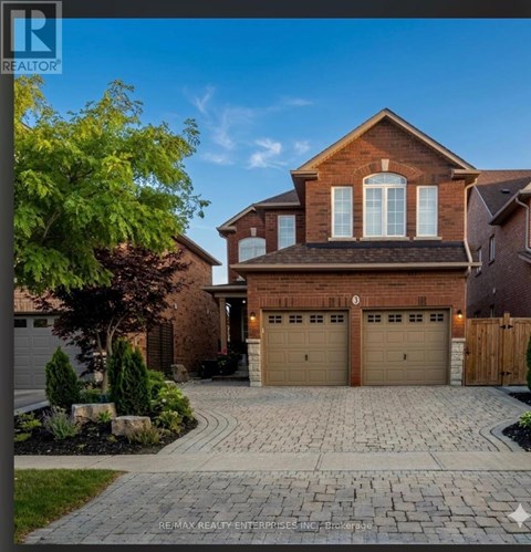 A house with a brick facade and a large driveway in front.