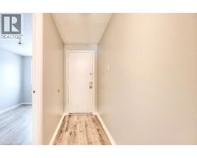 A hallway with a white door and wooden floor.