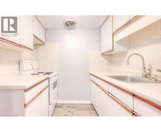 A small, white kitchen with a sink and a stove.