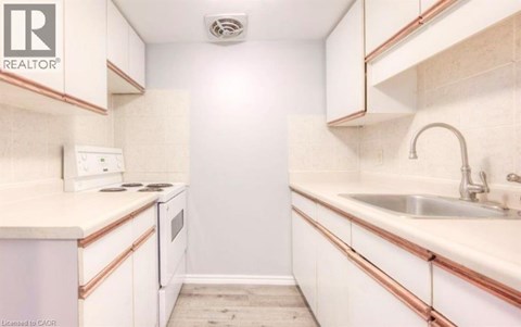 A small, white kitchen with a sink and a stove.