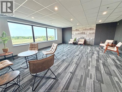 A conference room with a grey carpet and wooden chairs.