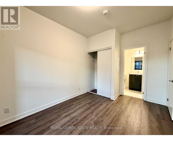 A room with wooden flooring and white walls, with a doorway leading to another room.