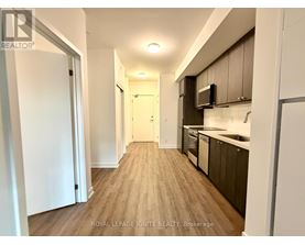 A well-lit hallway with wooden floors and modern appliances in a residential building.