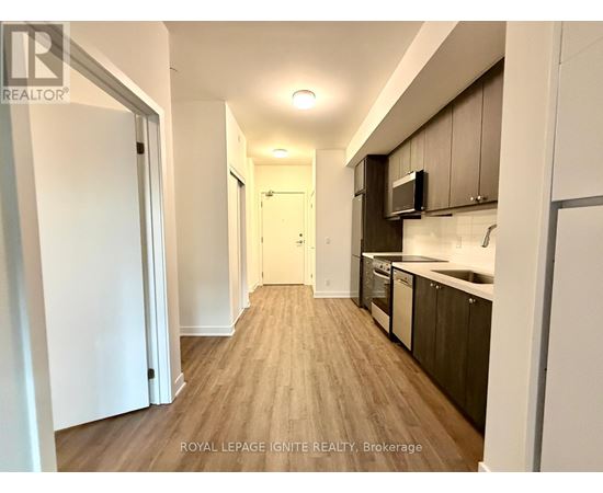 A well-lit hallway with wooden floors and modern appliances in a residential building.
