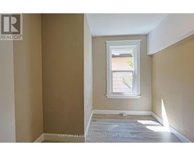 A room with a window showing a view of a house and trees outside.